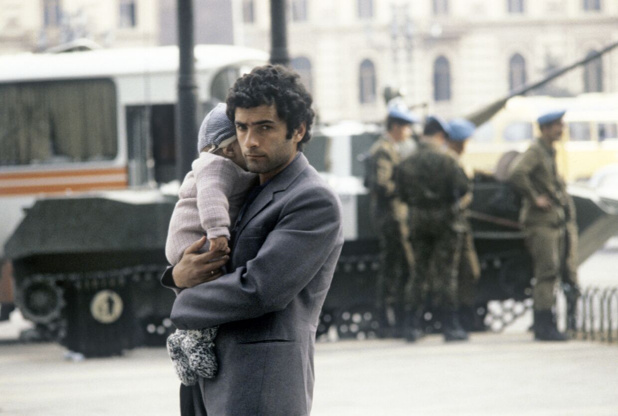 Мужчина с ребенком на фоне танка