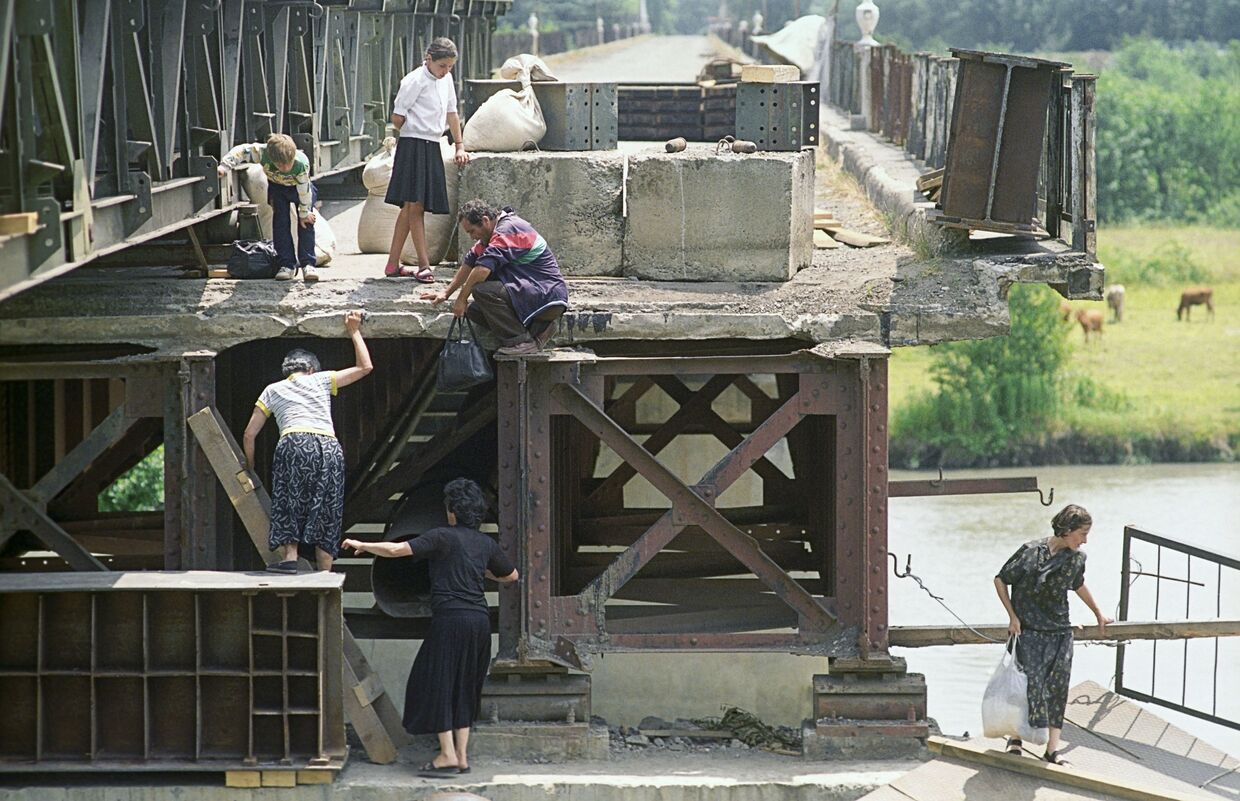 Беженцы возвращаются в Абхазию по разрушенному мосту через реку Ингури, 1993 год