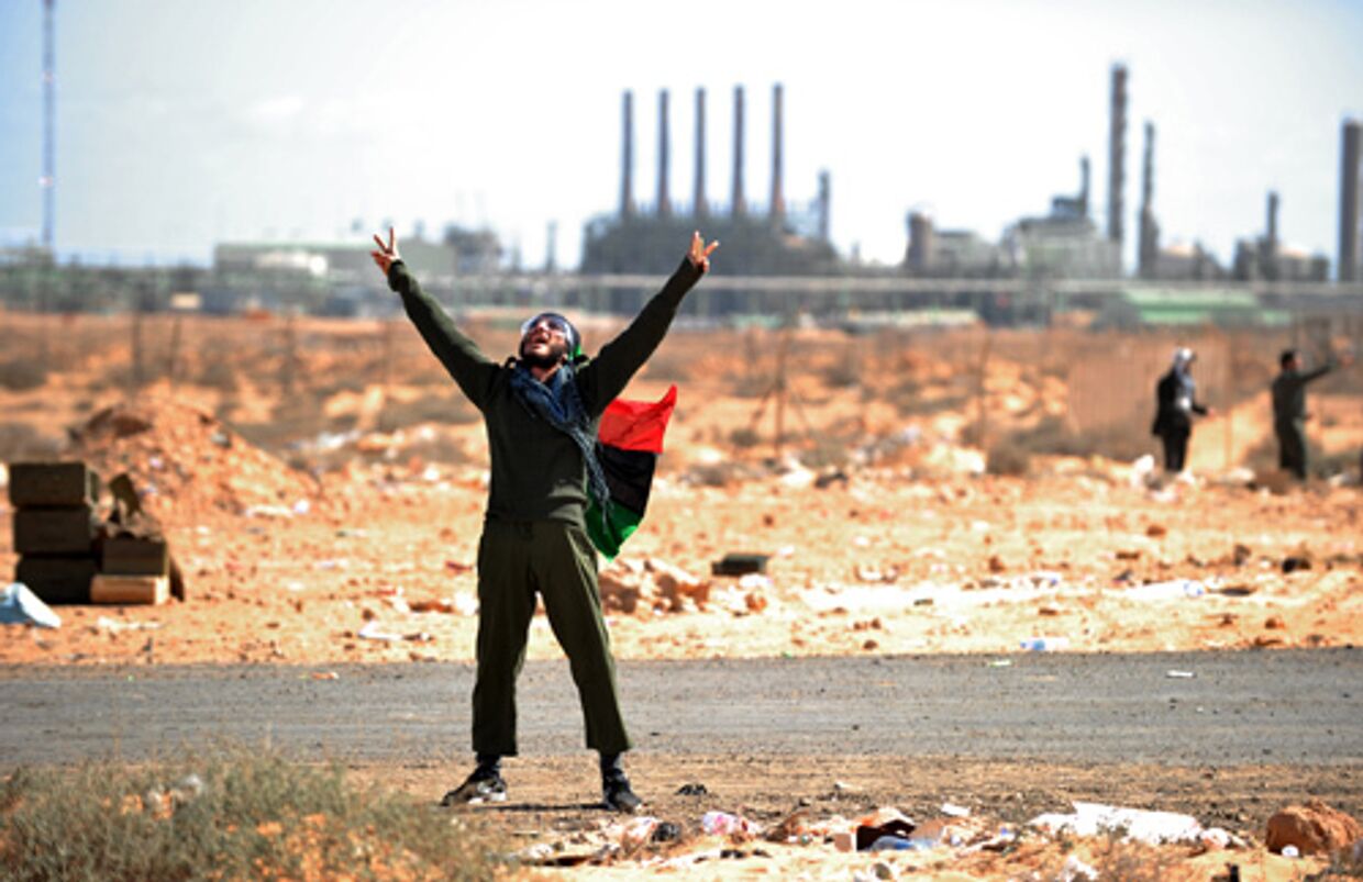 ливийский оппозиционер на фоне нефтяного завода в ливии