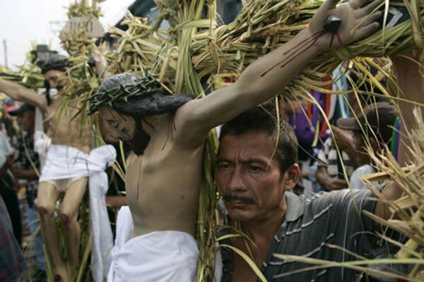Люди держат статуи Иисуса Христа, во время традиционной процессии во время Страстной недели в Сальвадоре