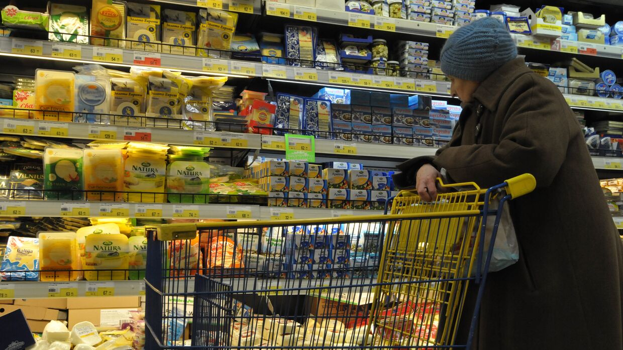 Пожилая женщина выбирает сыр в супермаркете