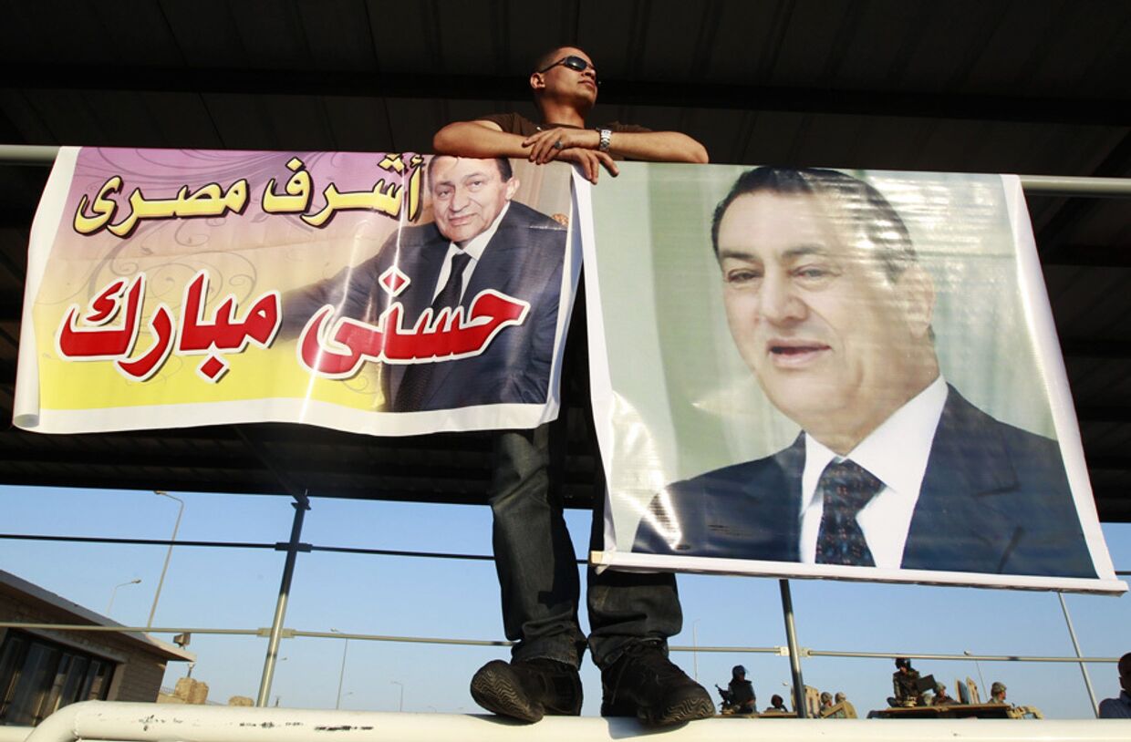 Сторонник бывшего президента Египта Хосни Мубарака стоит у плакатов с его изображением