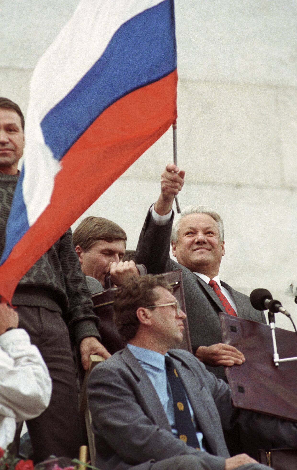 Президент России Б. Н. Ельцин стоит на трибуне с флагом
