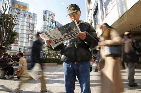 Мужчина читает газету с сообщение о смерти Ким Чен Ира в центре Токио 