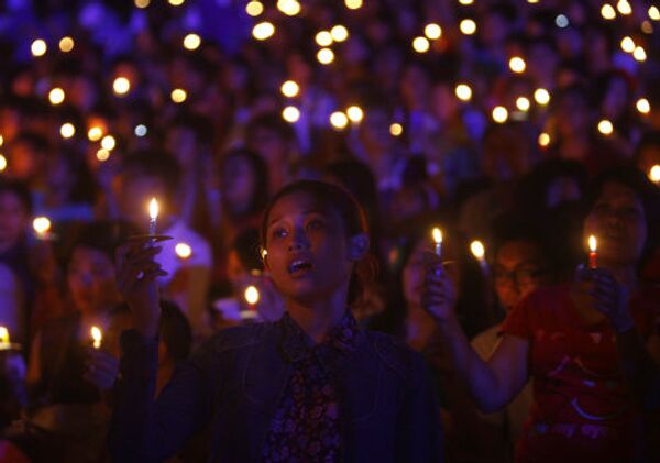 Индонезийские христиане держат свечи во время молитвы в канун Рождества в Джакарте