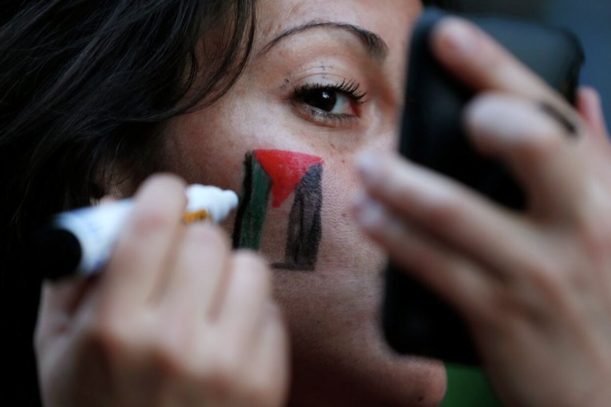 Девушка рисует на лице флаг Палестины