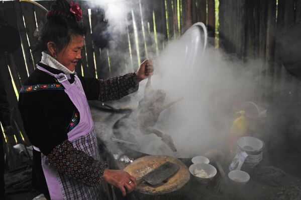 Представительница народности Мяо готовит угощение к празднику «Гуцзан» 