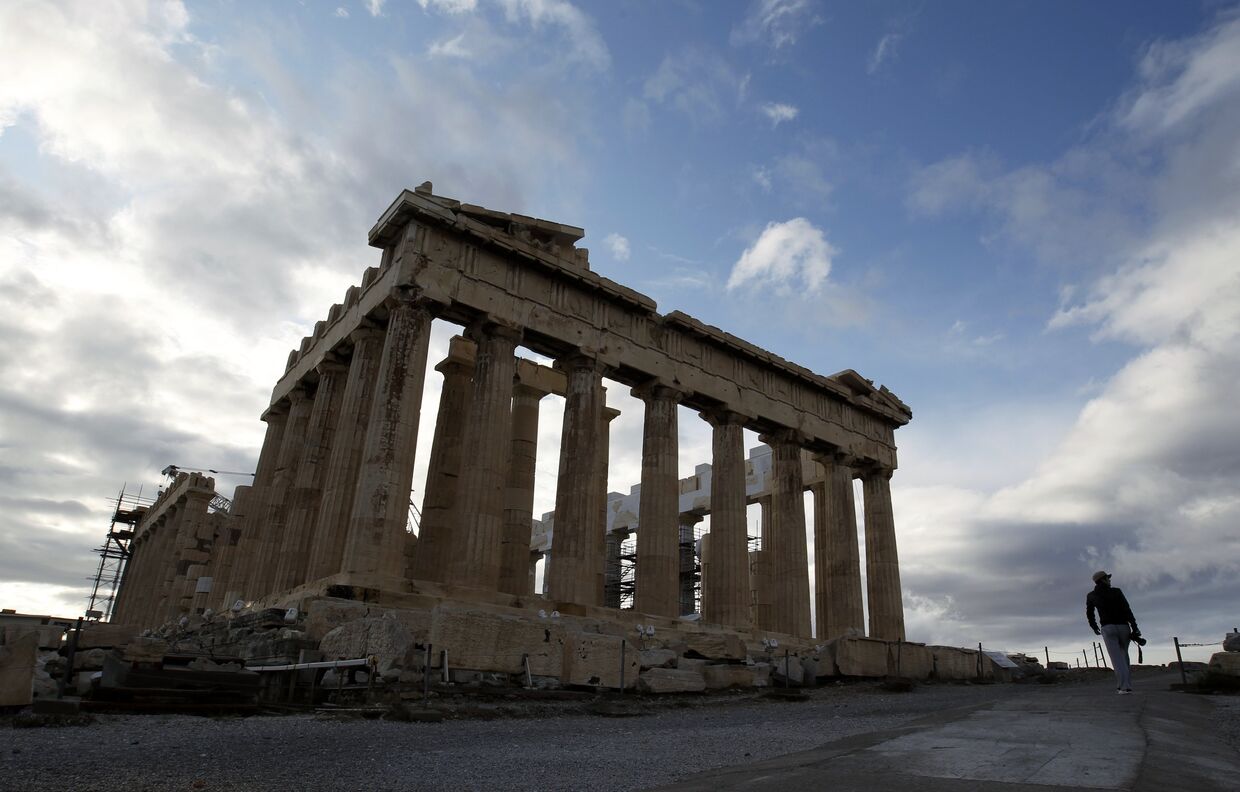Турист проходит мимо здания Акрополя в Афинах 