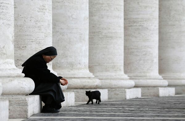 Монахиня сидит за колоннадой на площади Святого Петра в Ватикане