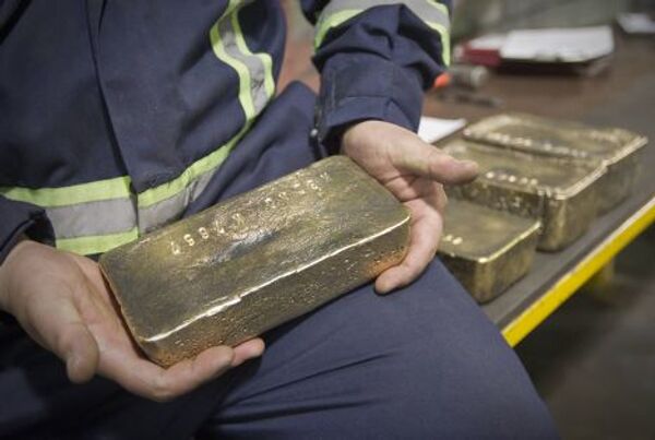 Работник рудника «Кумтор» держит слиток золота, Кыргызстан