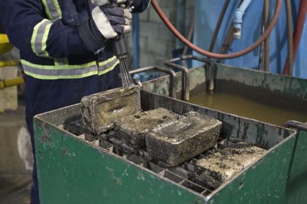 Работник рудника «Кумтор» чистит слитки золота, Кыргызстан