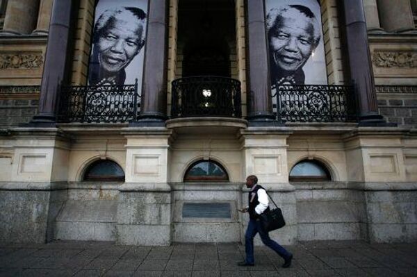 Мужчина проходит мимо баннеров с портретами Нельсона Манделы в Кейптауне