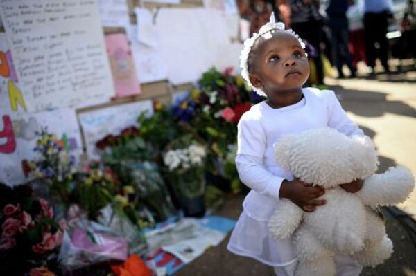 Девочка стоит возле плакатов в поддержку Нельсона Манделы в Претории