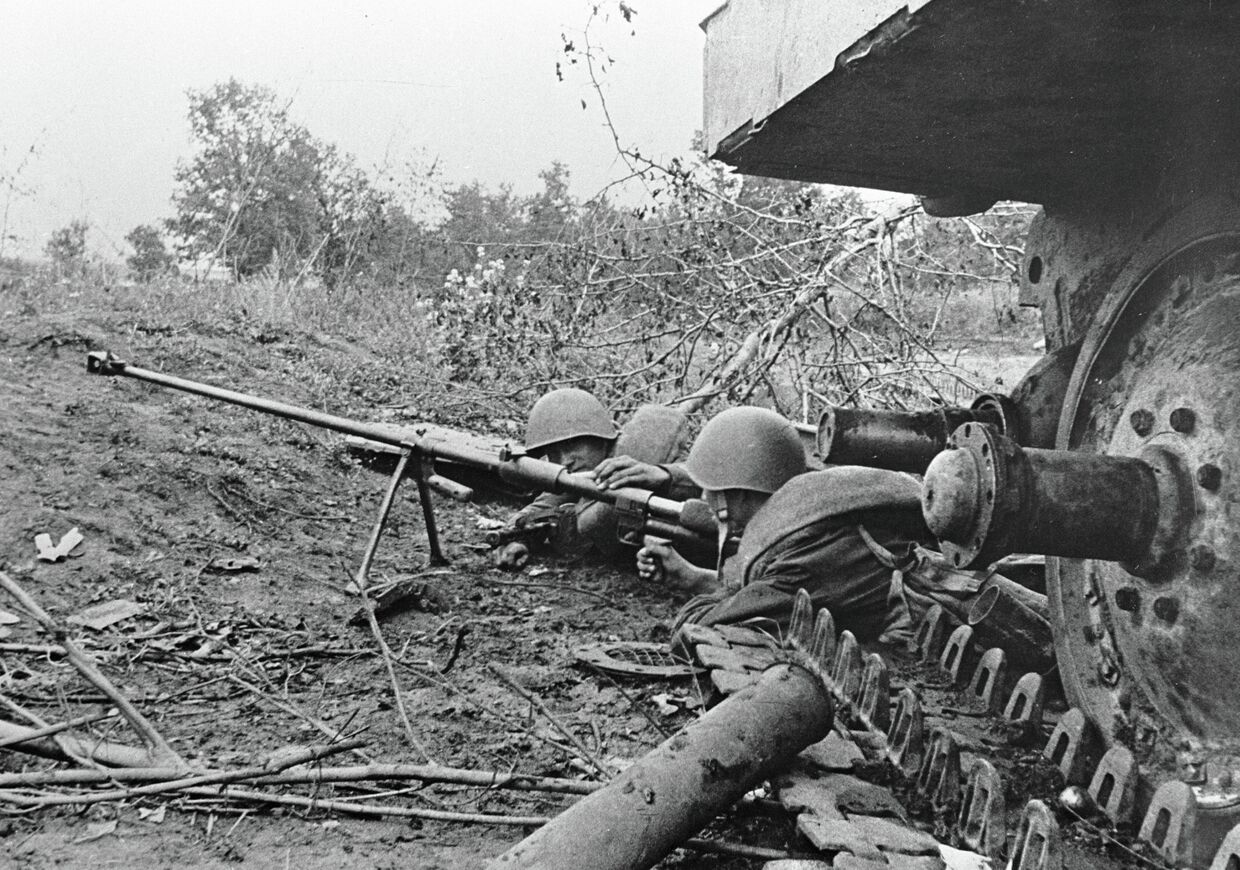 Гвардейцы-бронебойщики отражают танковую атаку врага, лежа рядом с подбитым танком. Курская дуга