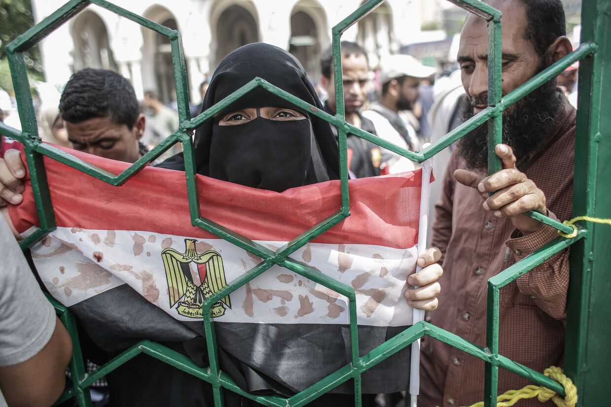 Женщина держит флаг Египта, на который кровью нанесены надписи