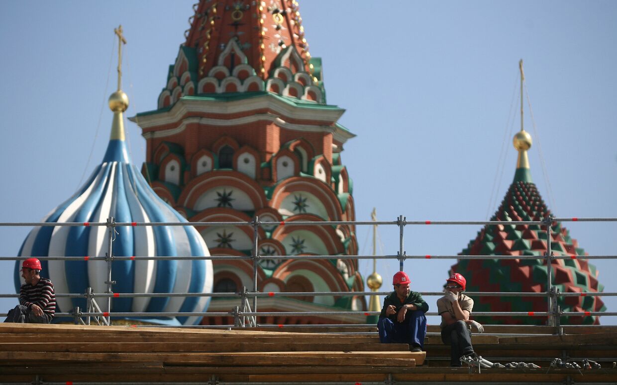 Рабочие отдыхают на строительных лесах на фоне Покровского собора на Красной площади.