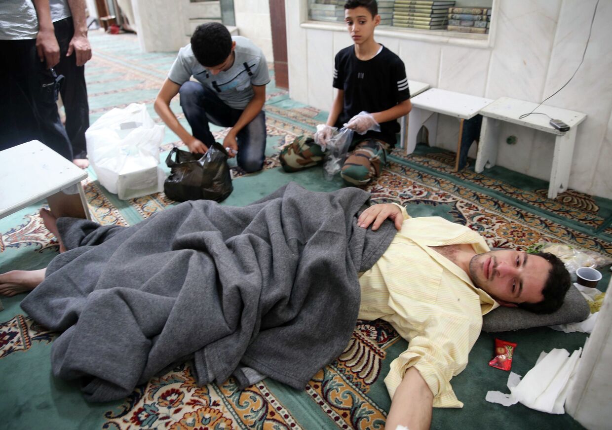 Люди помогают пострадавшим от газовой атаки в мечети в окрестностях Дамаска