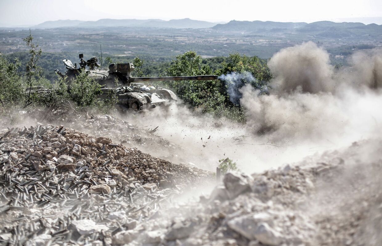 Танк правительственных войск ведет огонь по позициям боевиков во время боевых действий неподалеку от турецкой границы