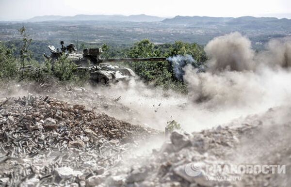 Танк правительственных войск ведет огонь по позициям боевиков во время боевых действий неподалеку от турецкой границы