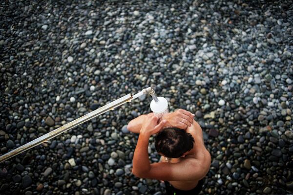 Отдыхающий принемает душ на пляже в городе Сочи