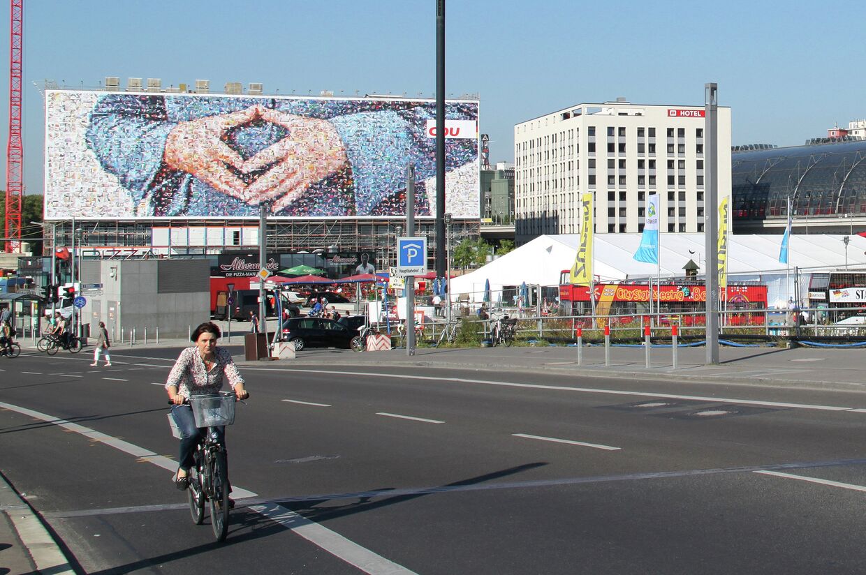 Агитационный плакат с изображением фирменного жеста Меркель у центрального вокзала Берлина