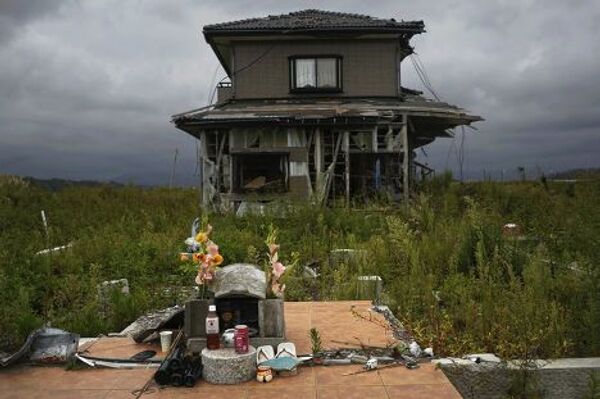 Памятник жертвам перед заброшенным домом в эвакуированном городе Нами, префектура Фукусима