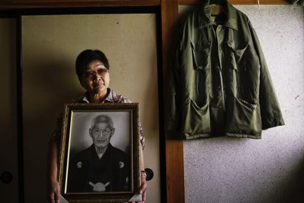 Миеко Окубо с портретом своего тестя, совершившего самоубийство после сообщения об эвакуации, префектура Фукусима