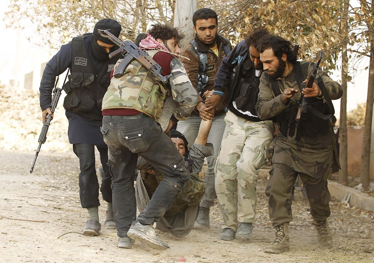 Солдаты Свободной сирийской армии несут тело товарища, раненого в столкновениях с правительственными войсками