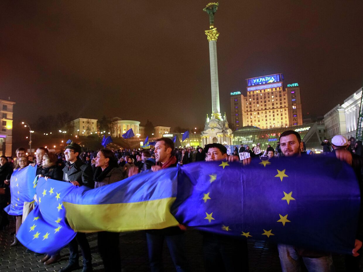 Протестующие держат украинские флаги и флаги Евросоюза во время митинга в поддержку евроинтеграции, Киев
