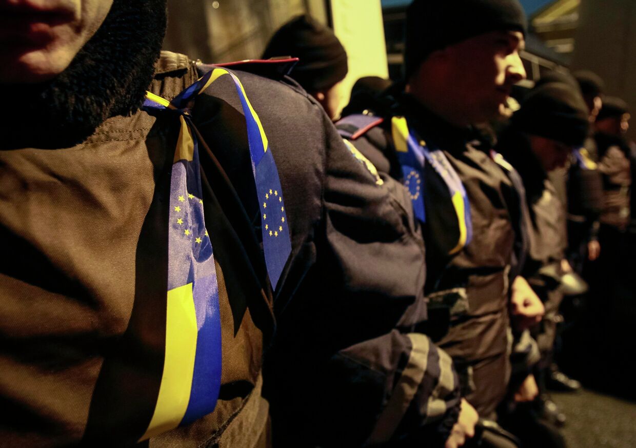 Ленты с украинскими флагами и флагами Евросоюза на полицейских во время митинга в поддержку евроинтеграции, Киев
