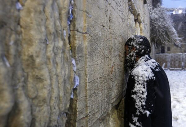 Ультраортодоксальный еврей молится у стены Старого города после снегопада в Иерусалиме
