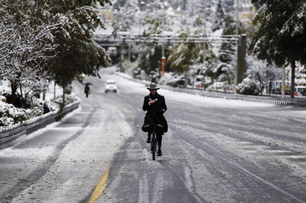Ультраортодоксальный еврей едет на велосипеде по улице Иерусалима после сильного снегопада