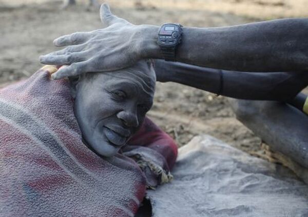 Человек из племени динка натирает своему другу голову пеплом 