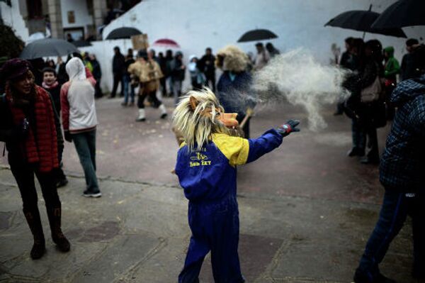 Мальчик в маске бросает опилки в посетителей карнавала в деревне Зубиета в Испании