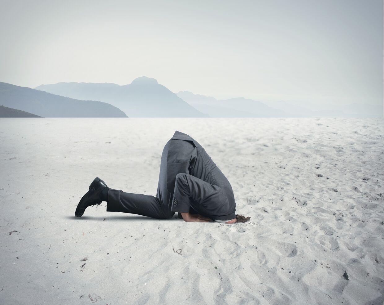 Человек прячет голову в песок