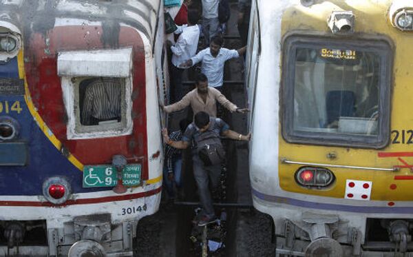 Люди переходят железнодорожные пути на станции в Мумбаи, Индия