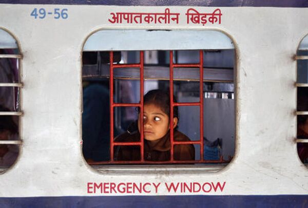 Девочка смотрит в окно поезда на станции Ахмадабад, Индия 