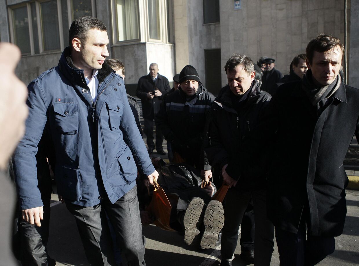 Виталий Кличко держит носилки с пострадавшим во время столкновений в Киеве