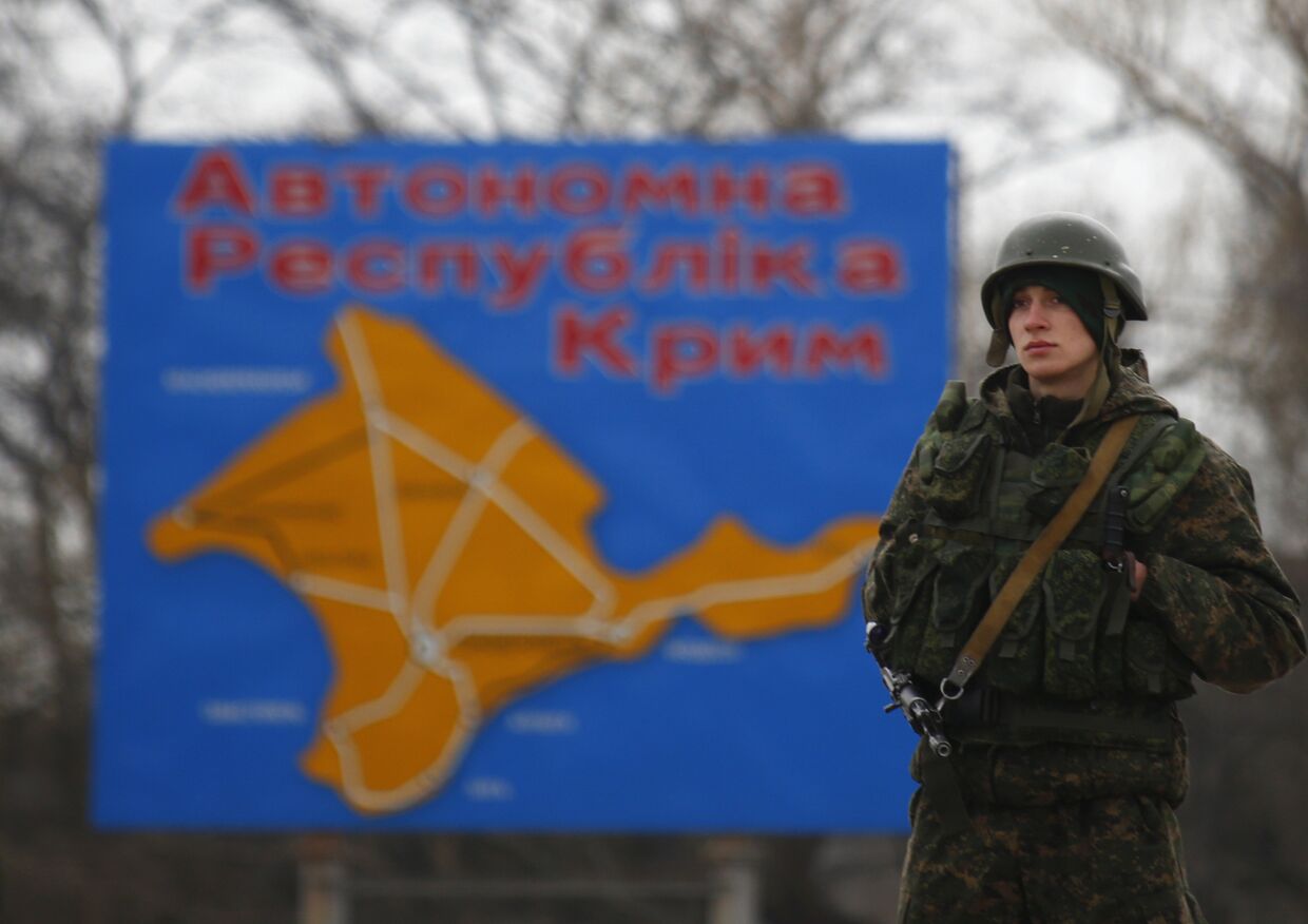 Российский военнослужащий на фоне карты Крыма рядом с городом Керчь