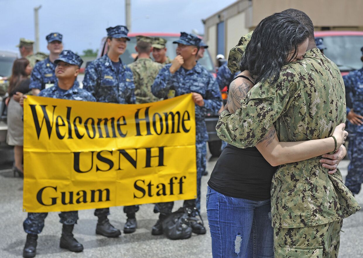 Моряк, вернувшийся из четырехмесячного плавания по Юго-Восточной Азии, обнимает жену на острове Гуам