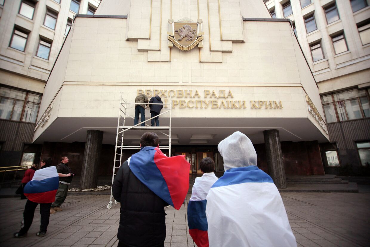 Рабочие снимают вывеску Верховной Рады Автономной республики Крым на украинском языке.