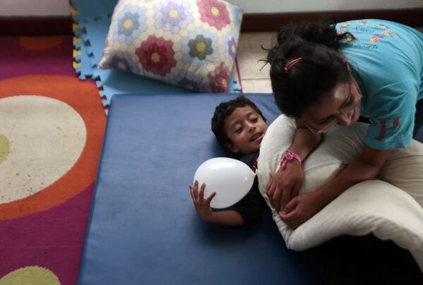 Девушка-волонтер играет с ребенком в Терапевтическом и развивающем центре для детей, больных аутизмом, в Гватемале