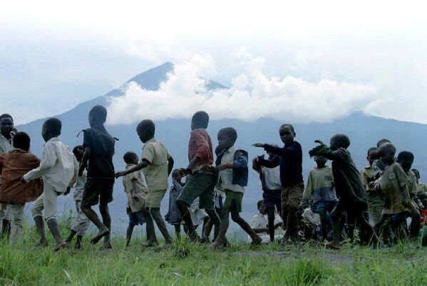 Дети танцуют на фоне вулкана в лагере для беженцев из Руанды