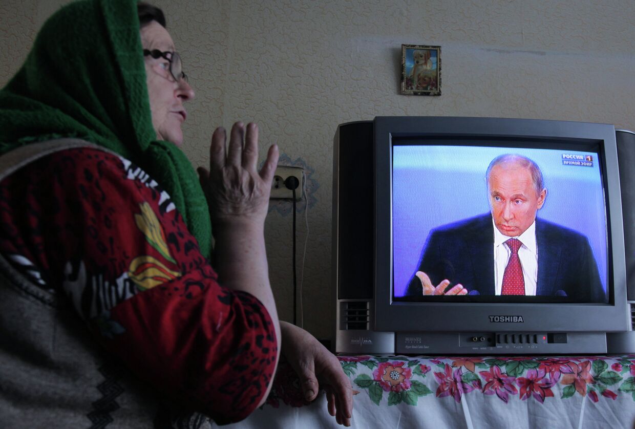 Жительница деревни Фрунзе Омской области смотрит телетрансляцию пресс-конференции президента России Владимира Путина.
