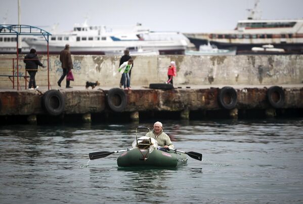 Человек плывет на лодке рядом с набережной в Ялте