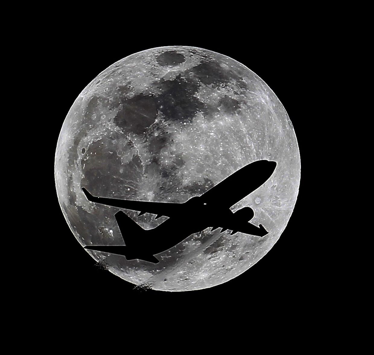 Силуэт самолета на фоне луны за час до полного лунного затмения