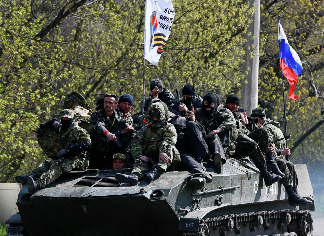 Люди, одетые в военную форму на боевой технике с флагом России в Славянске