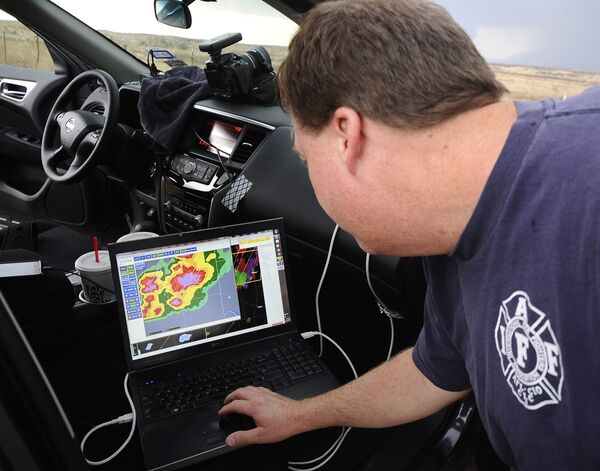 Охотник за грозами Брэк Мэк смотрит на экране своего ноутбука, как суперъячейковая гроза проходит над городом Эрик, штат Оклахома
