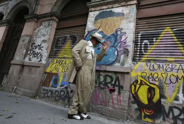 Даниэль Рамирес в своем костюме в стиле пачуко у покрытой граффити стены в Мехико