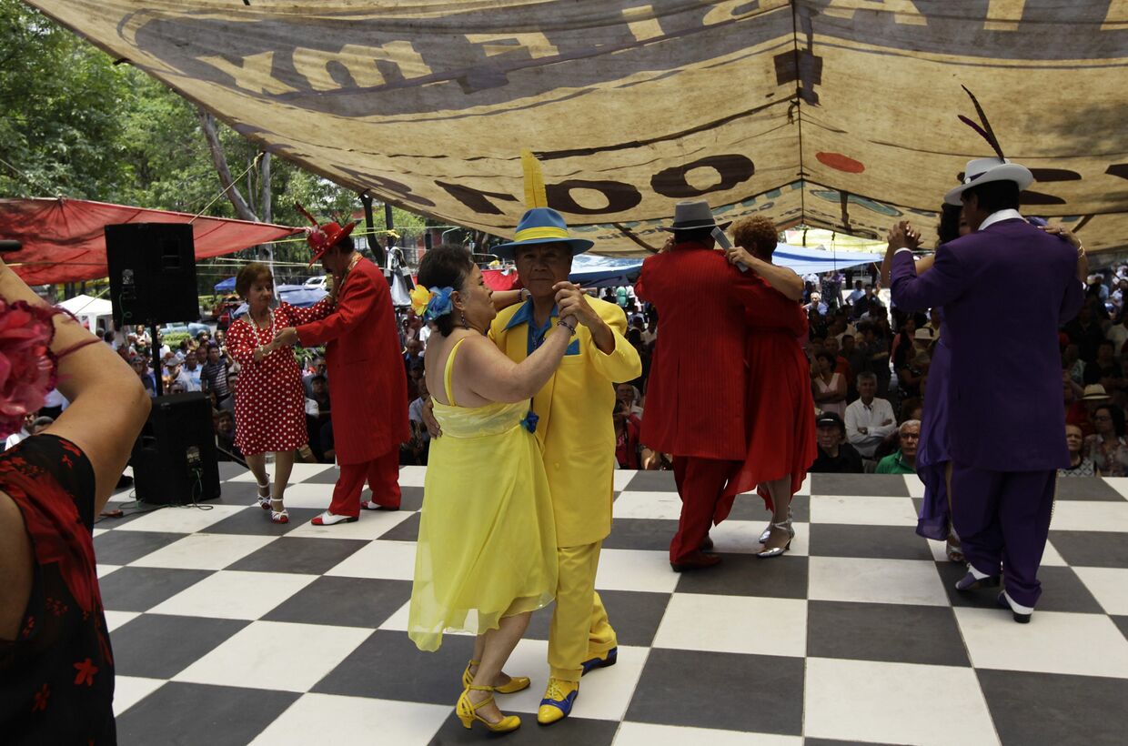 Мужчины в костюмах в стиле пачуко танцуют с женщинами, одетыми в стиле румберас